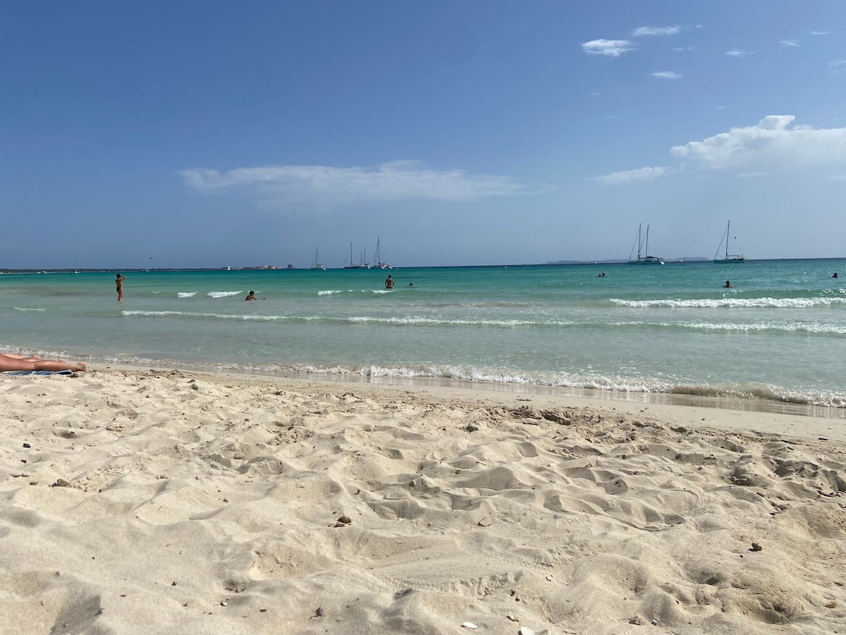 Flach abfallender Sandstrand von Sa Ràpita mit türkisblauem Wasser und Segelbooten vor Mallorca